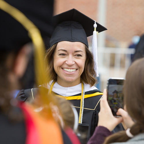 Looking over the shoulder of a CU Denver graduate at a woman posing for a photo