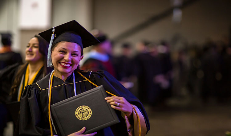 A graduate posing and smiling