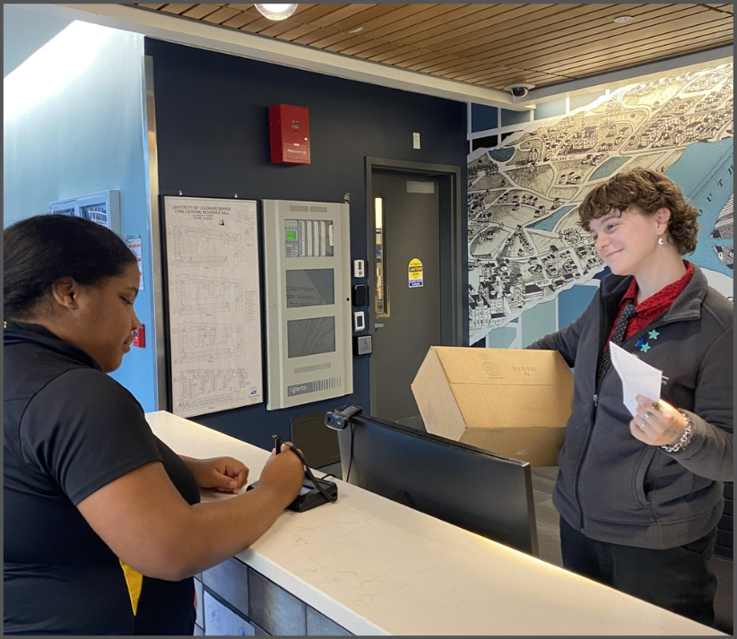 A Desk Assistant Handing a Resident their letter and their box