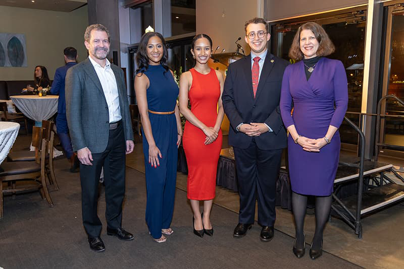 Five people dressed in professional clothing stand side-by-side smiling.