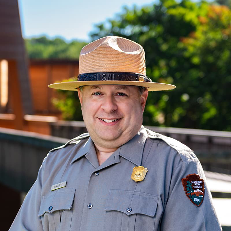 Ken Bigley in a National Park Service uniform smiling with his teeth.