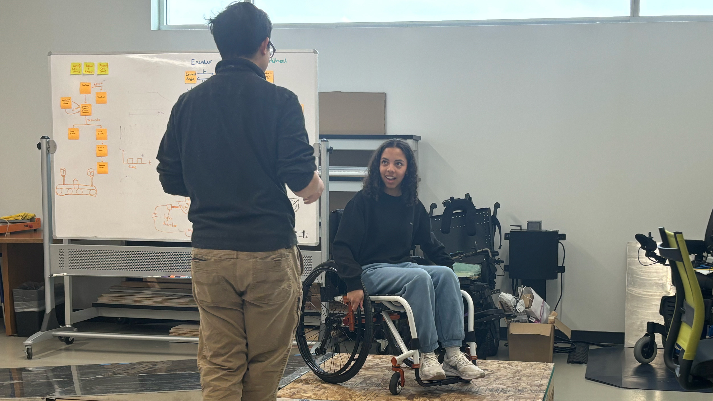 Highschooler tries out wheelchair ramp while speaking with CIDE researcher, Dr. Morris Huang