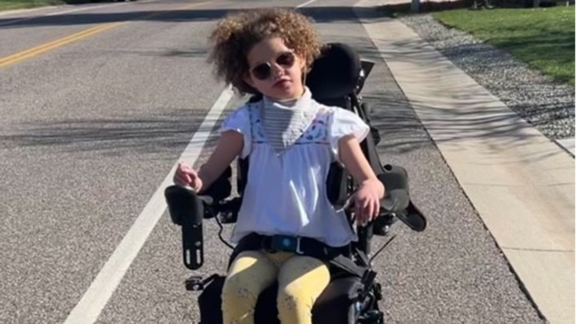 Jordy rides down a neighborhood street in her new chair