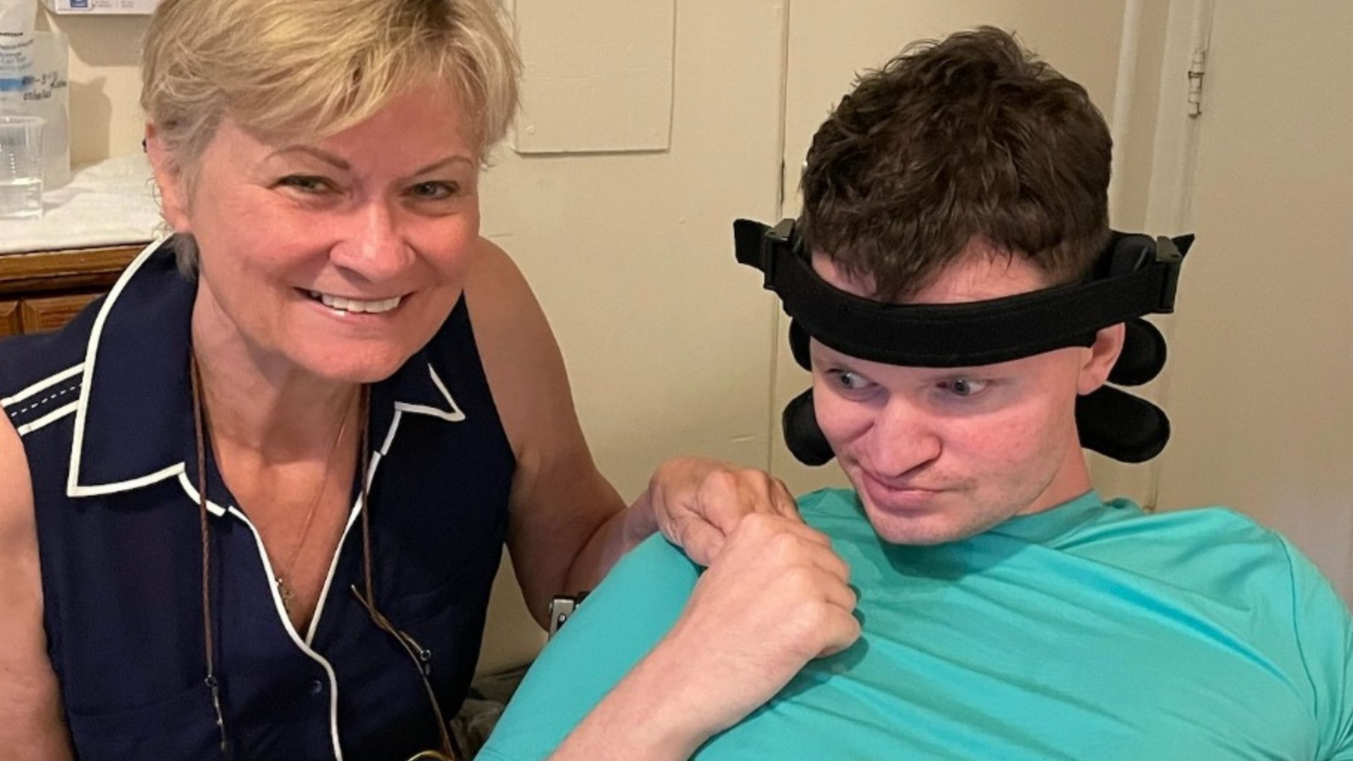 A young man in a wheelchair holds his mom's hand