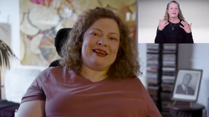 A woman in a wheelchair speaks while an interpreter signs