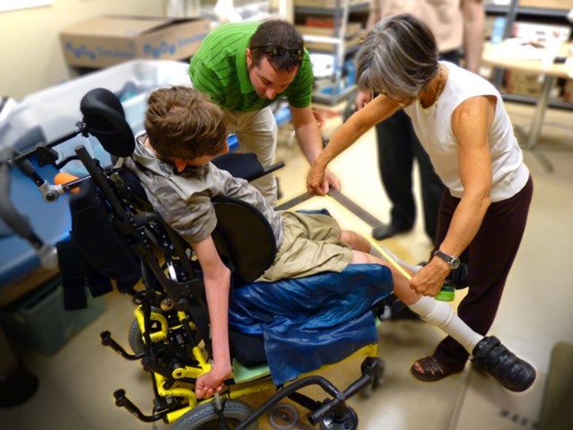 A physical therapist works alongside a wheelchair supplier to measure the optimal seating angles for a client.